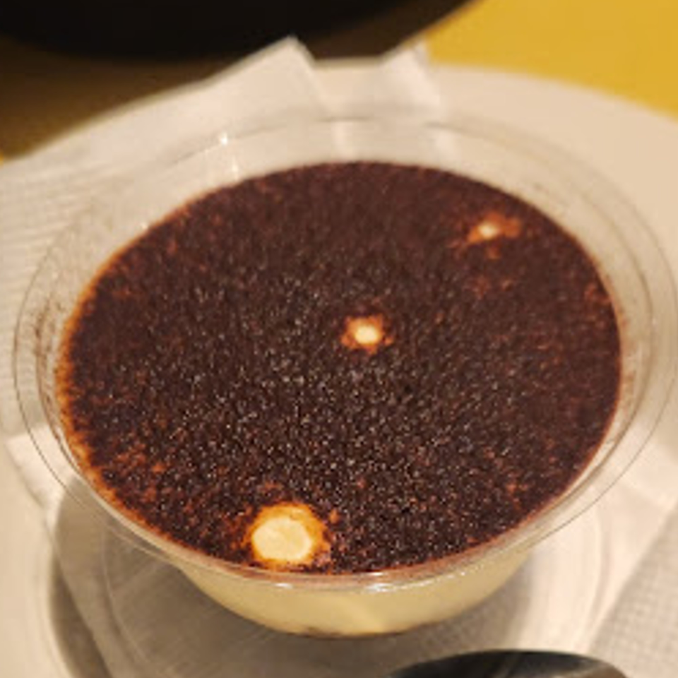 Coppola's Pizzeria & Italian Restaurant's tiramisu dessert in a clear plastic cup, topped with cocoa powder.