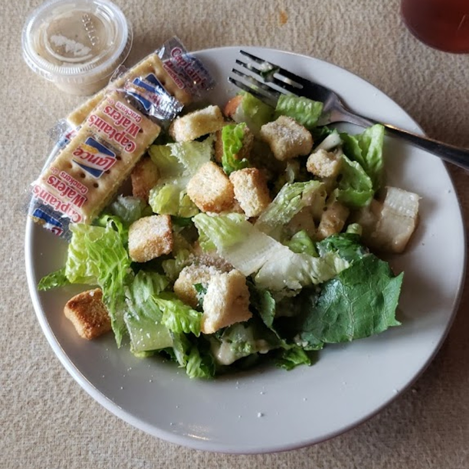Caesar salad with croutons, dressing, and crackers on a white plate at Coppola's Pizzeria.