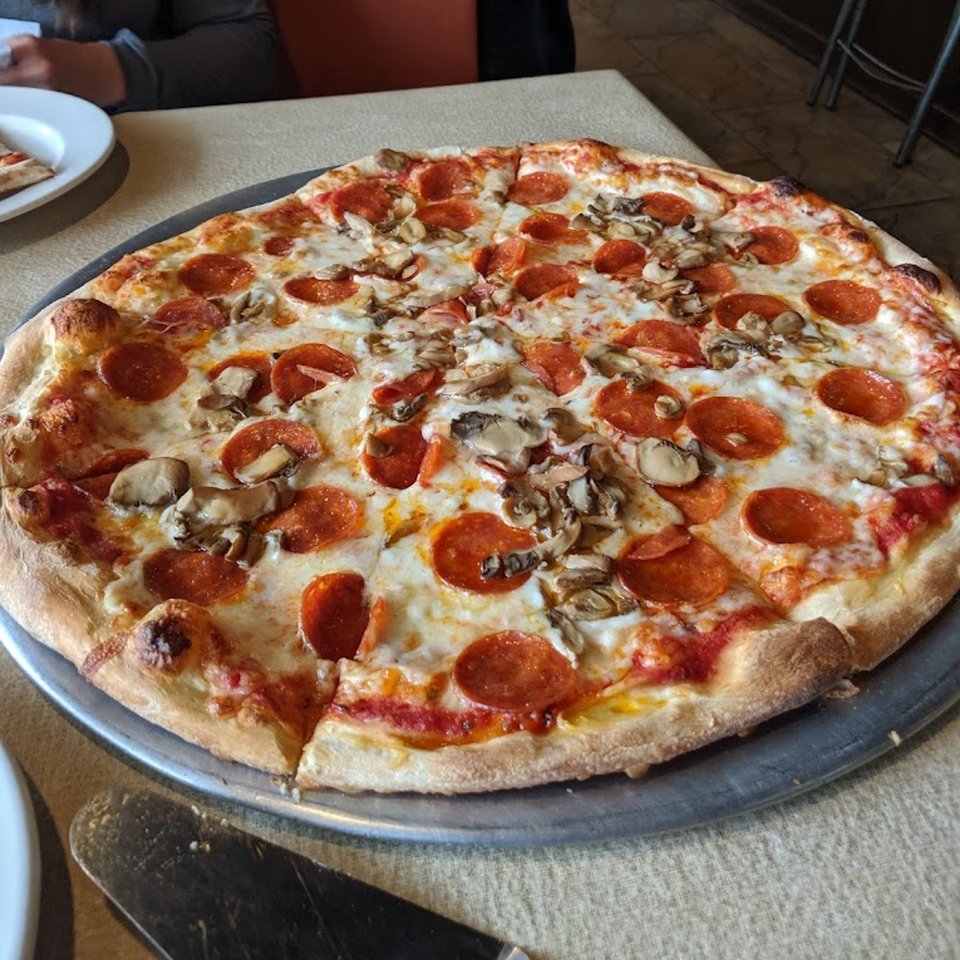 A large, round Coppola's pizza with pepperoni and mushrooms on a metal tray.