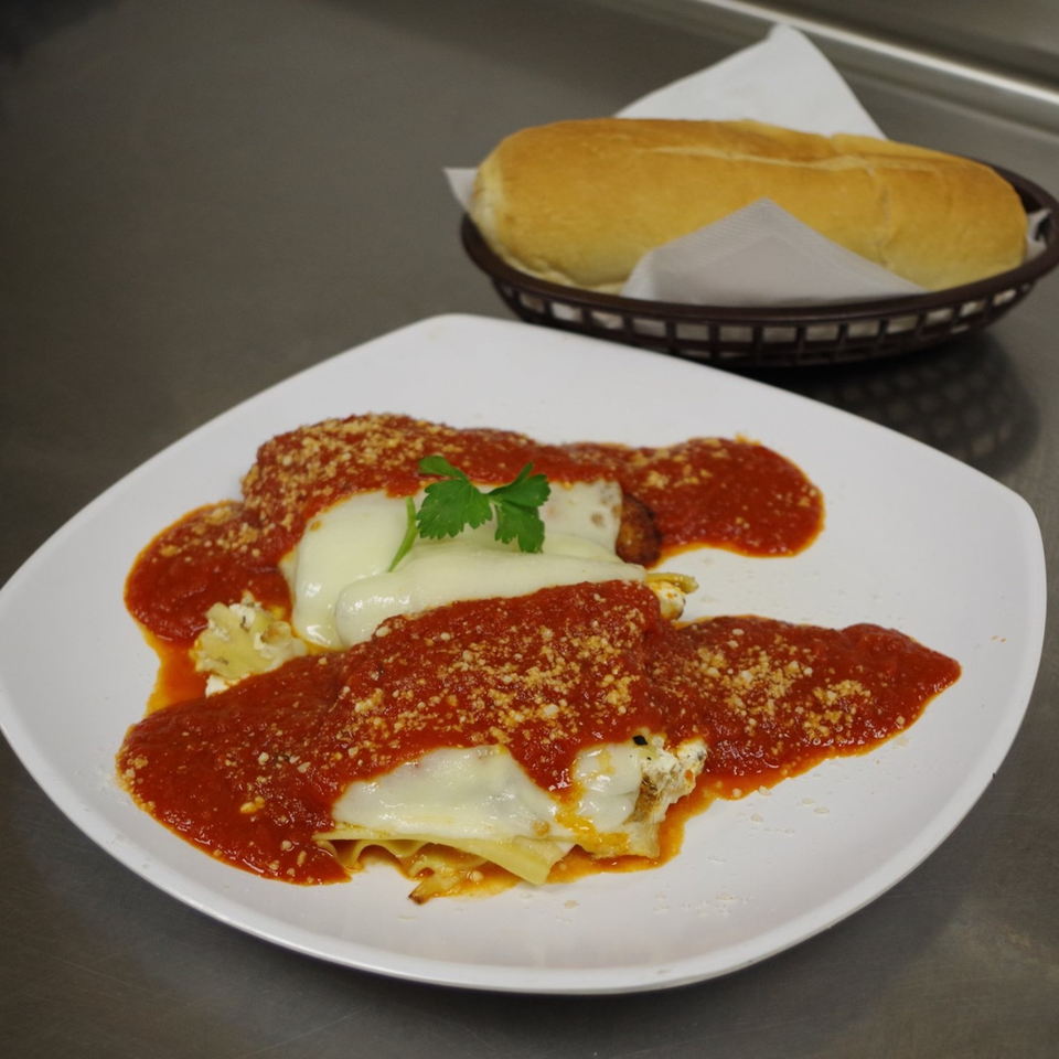 Coppola's baked lasagna with red sauce, melted cheese, and a side of bread.